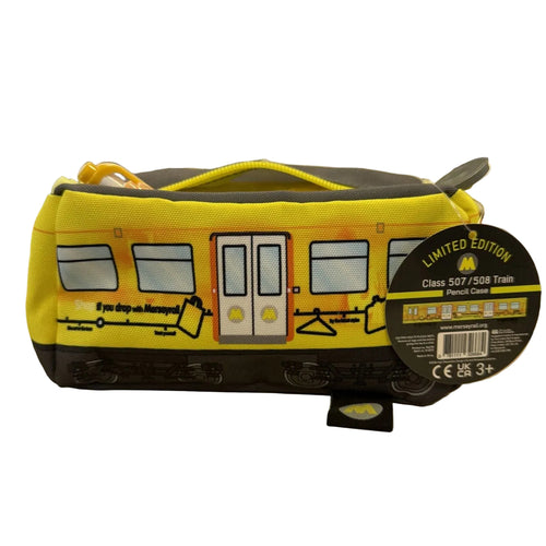 A yellow and black novelty pencil case designed to look like a subway train car, sitting on a wooden desk with a blurred office background. A round black hangtag on the right reads 'LIMITED EDITION Class 507/508 Train'.
